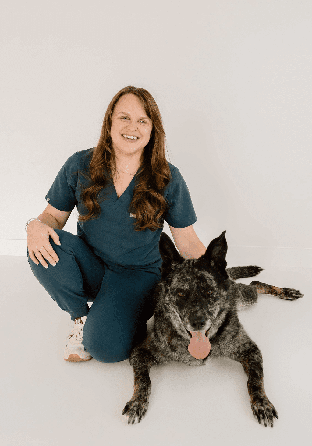 Dr. Jordan - female veterinarian kneeling down by large dog with a mix of black and gray fur